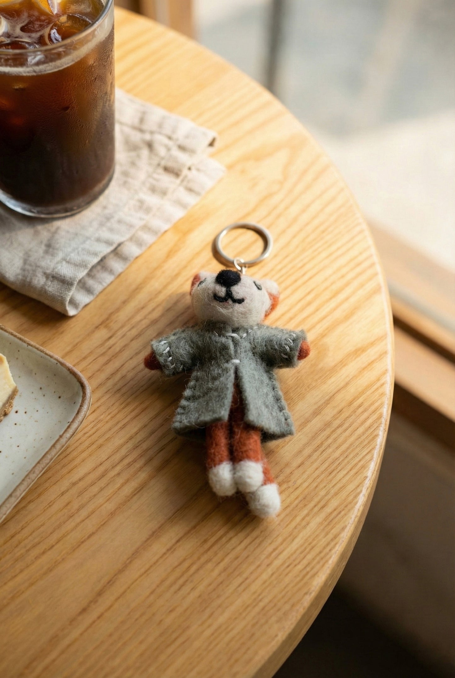 rey coat raccoon wool felt keychain on round wooden table at coffee shop