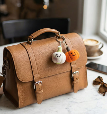 Felt vegetable keychains on brown leather satchel with coffee