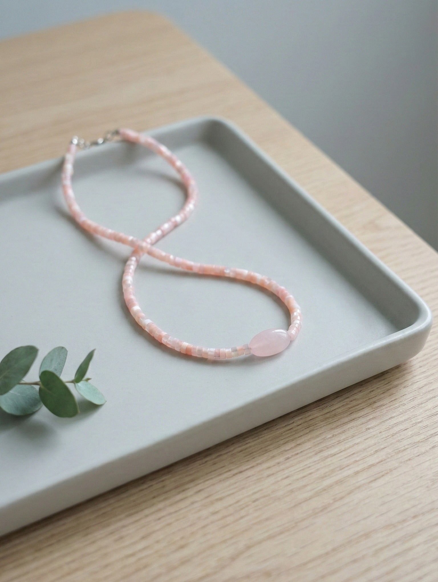 Rose quartz pink gemstone choker with matching shell beads on white plate