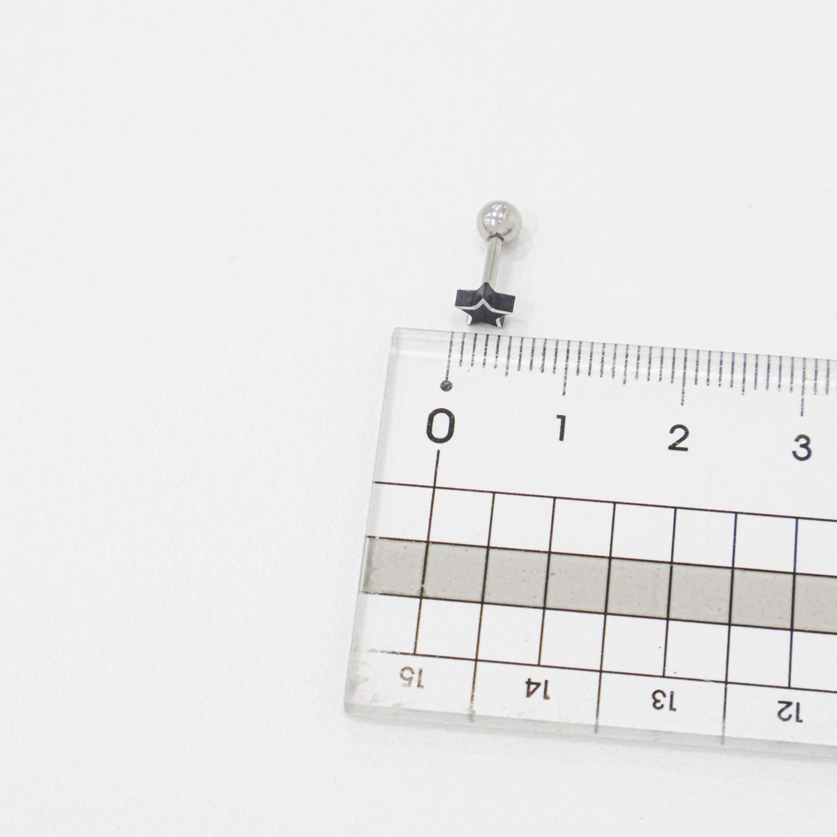 Black star cartilage stud next to measuring ruler showing 6mm size
