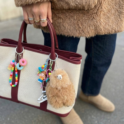 Canvas tote bag with burgundy handles featuring fluffy alpaca keychain and colorful beaded charms, cottagecore style accessories