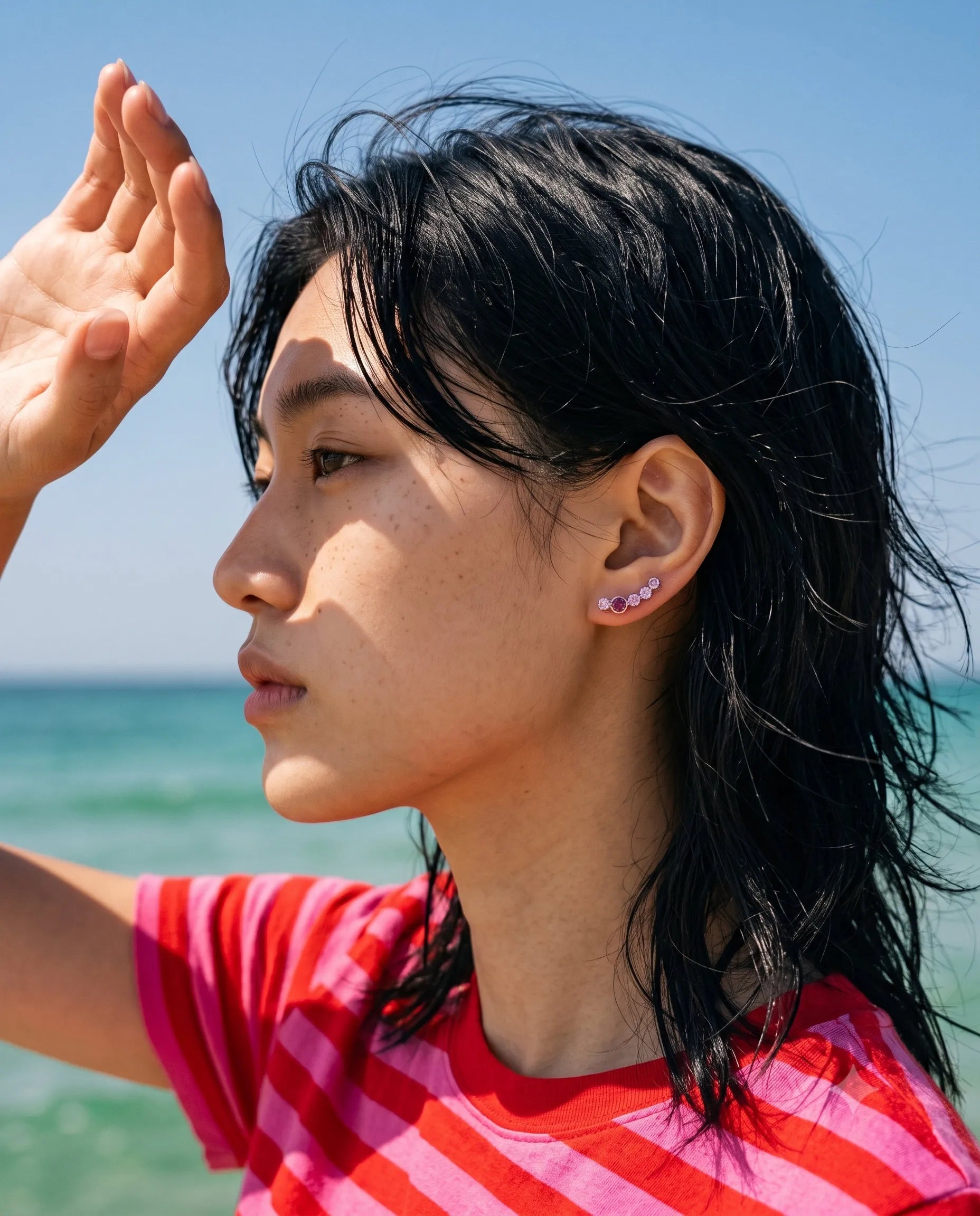 Ruby and amethyst bezel ear climber earrings on model wearing red stripe tee at beach – K-style summer jewelry
