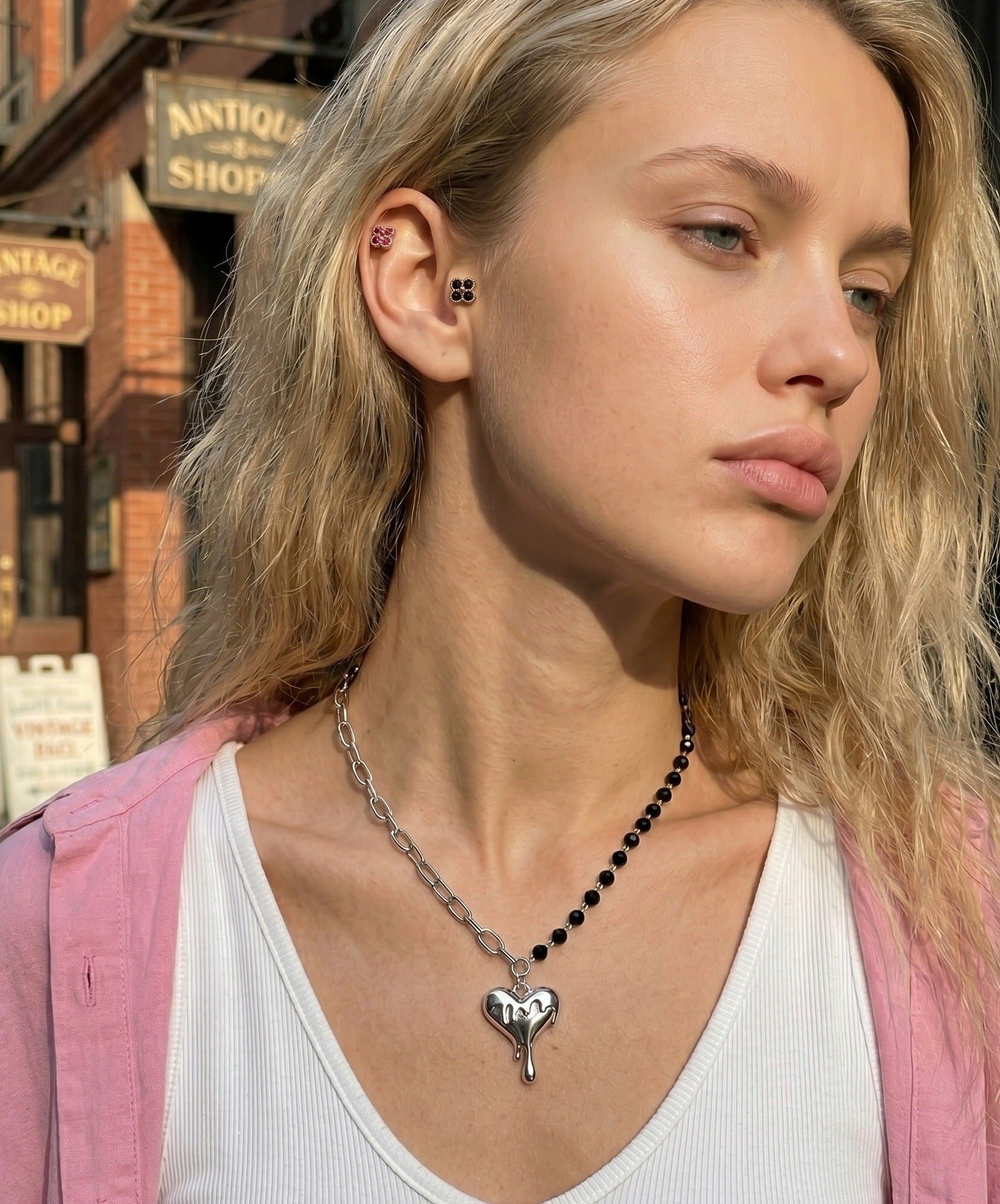 Downtown girl aesthetic melting heart black crystal bead half chain necklace with clover CZ curated ear piercing stack, K-street style editorial outdoor look.