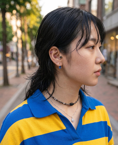 K-fashion editorial ear stack inspo — Oval Bezel Emerald CZ Huggie Earrings on model with wet hair freckles, layered with clover piercing for curated ear look.