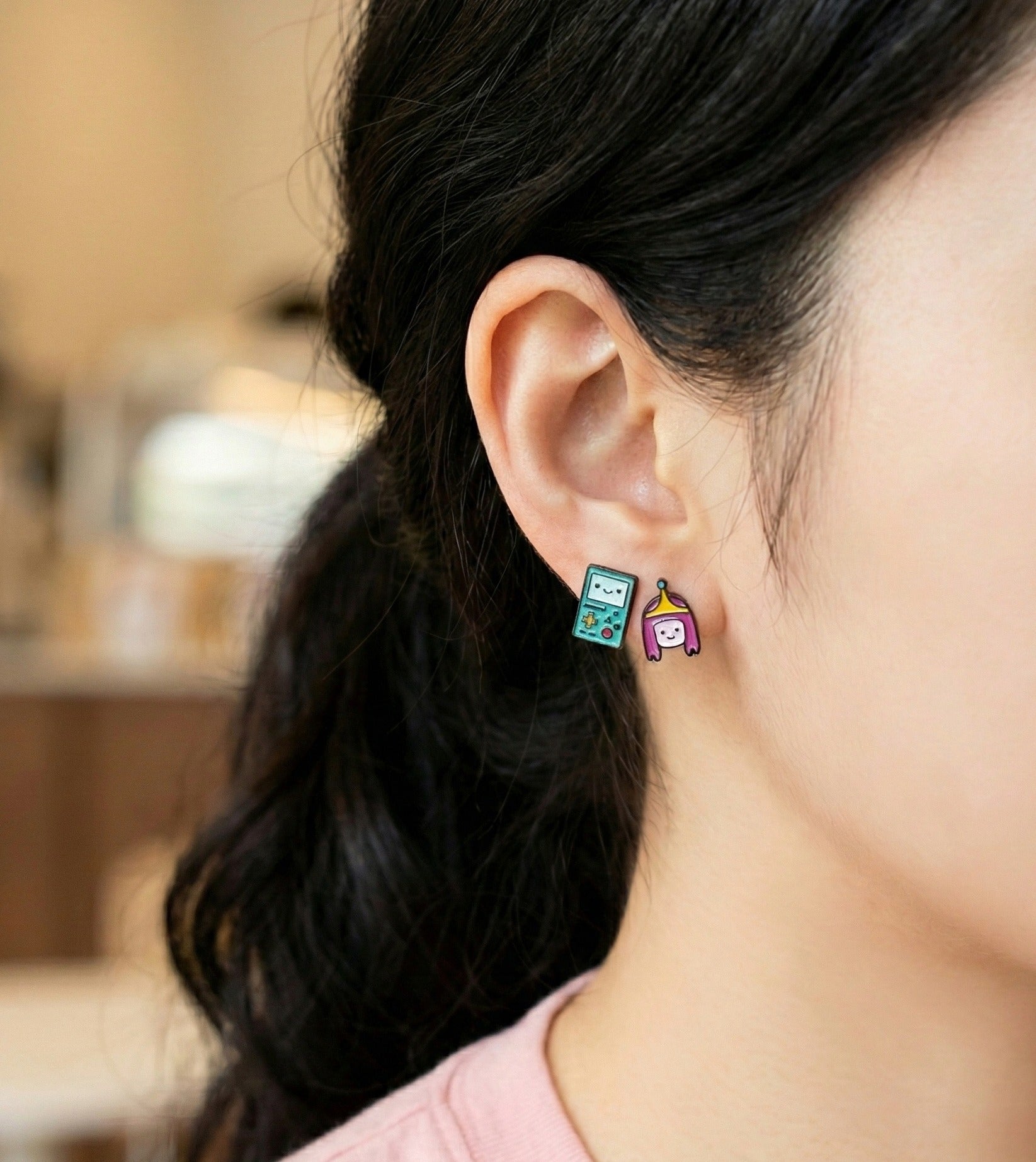 Side profile woman wearing Adventure Time BMO and Princess Bubblegum stud earrings minimalist style
