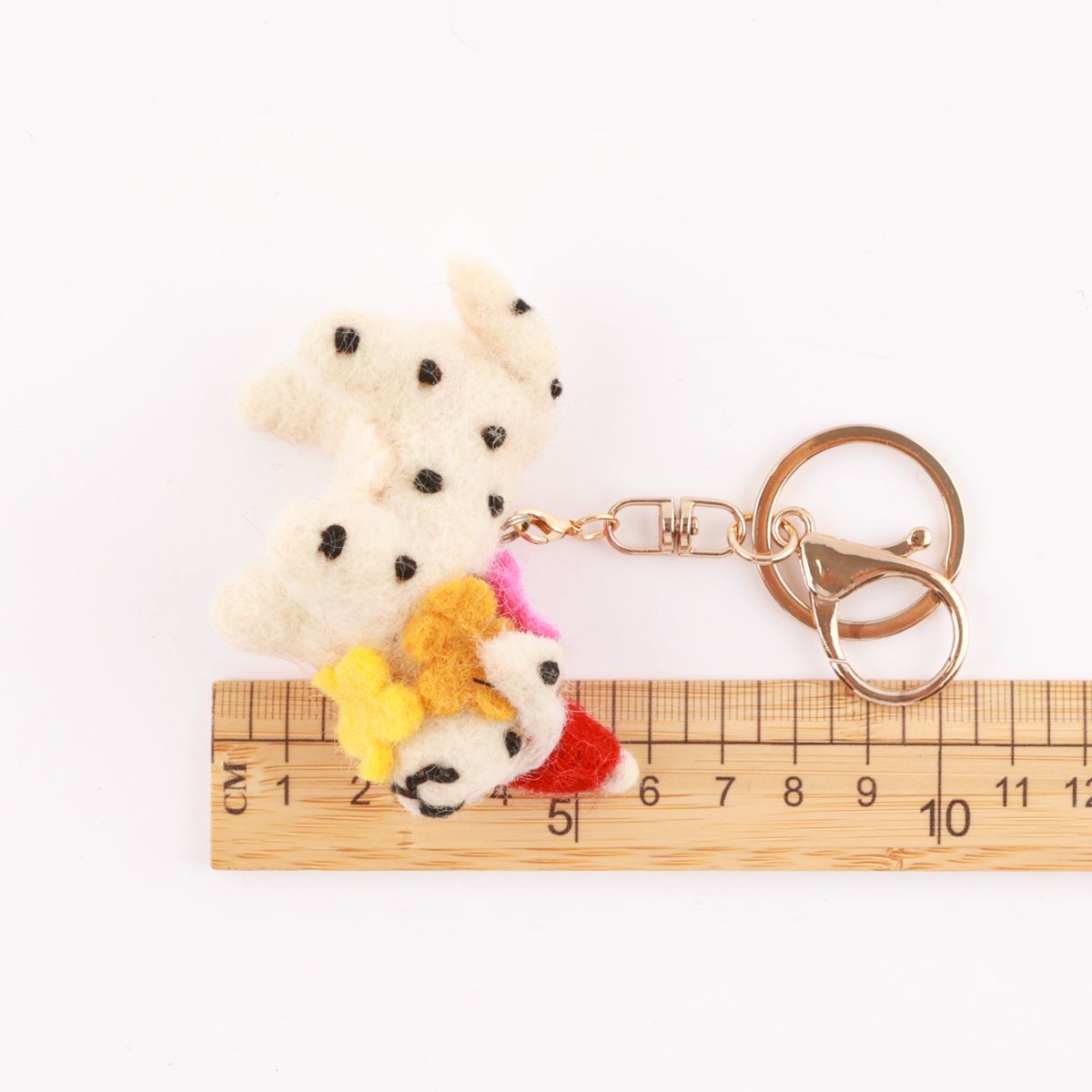 Size reference photo showing wool felt Dalmatian keychain next to wooden ruler measuring approximately 8cm