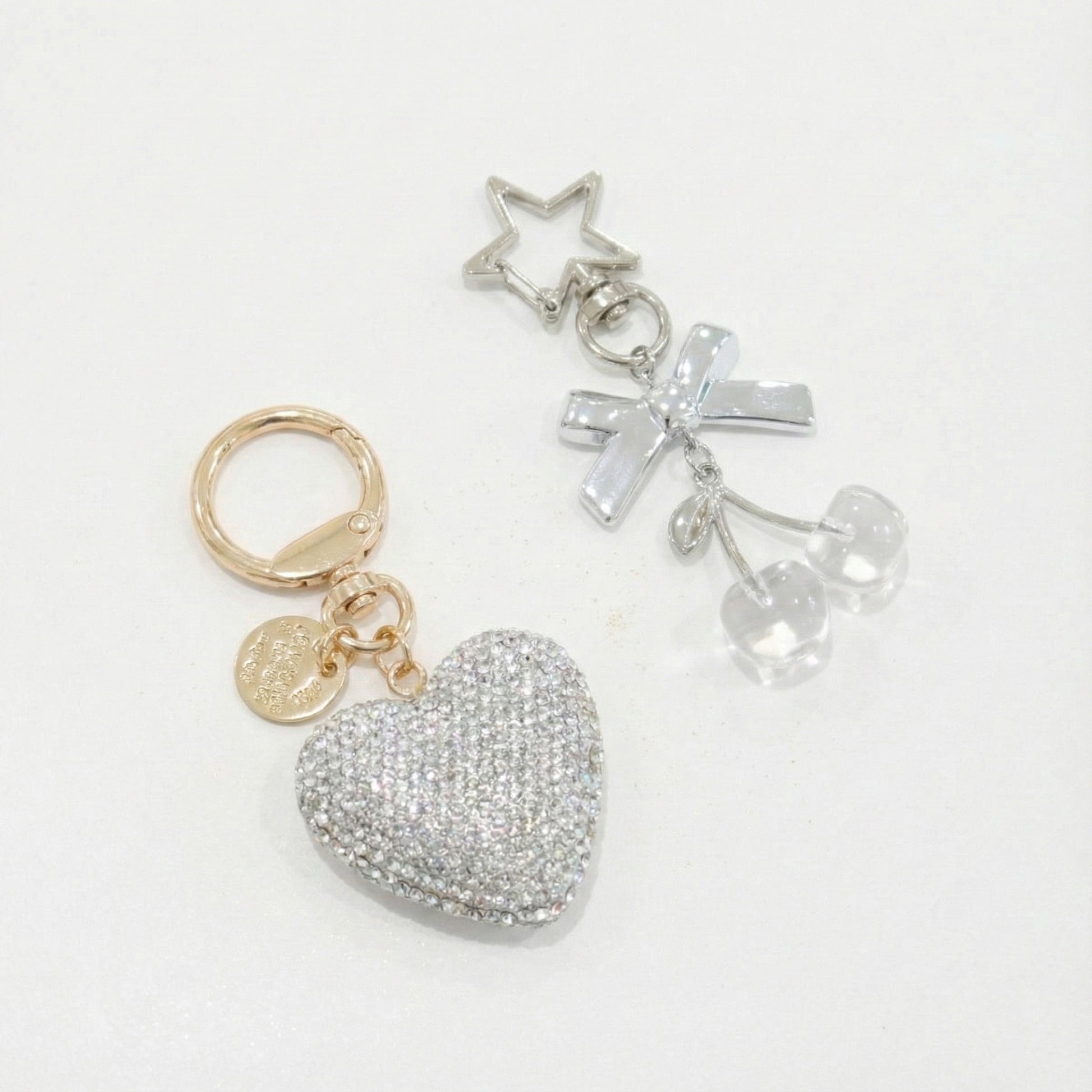 Silver rhinestone heart and transparent cherry charm keychain with silver bow and star, styled on white background