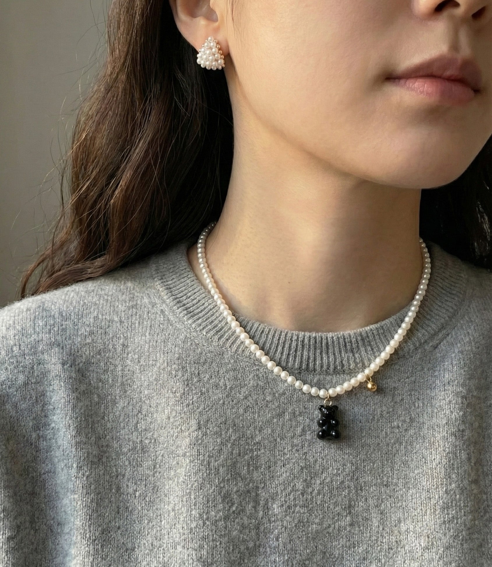 Full styling shot of pearl necklace with black gummy bear charm and heart earrings