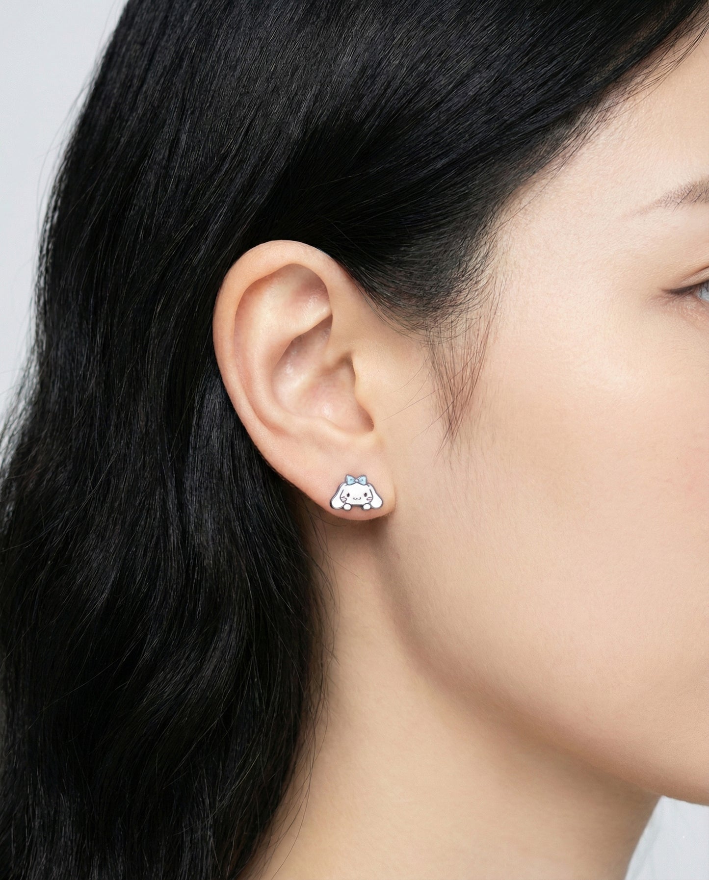Angle view of Cinnamoroll style character earrings showing both left and right designs