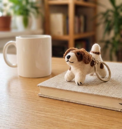 Handmade wool felt spotted dog keychain on wooden desk with coffee mug