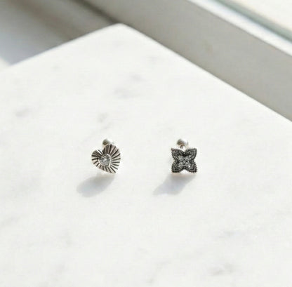 Antique silver heart and flower cartilage stud earrings with engraved details on white background