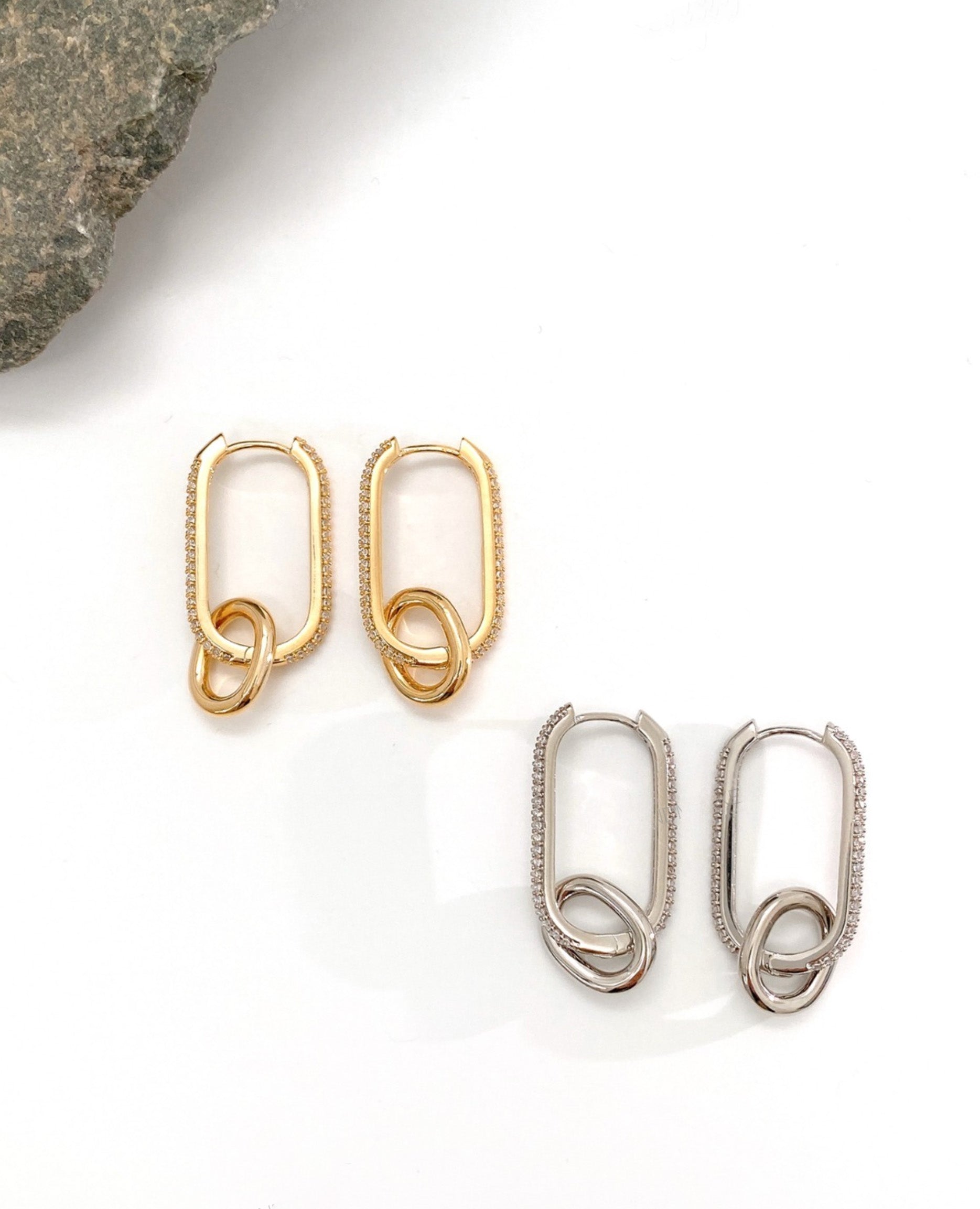 Flat lay of gold and silver oval link drop earrings, both pave options displayed