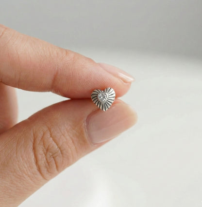 Close-up of radiant heart cartilage stud with ray engravings and cubic zirconia center held in hand