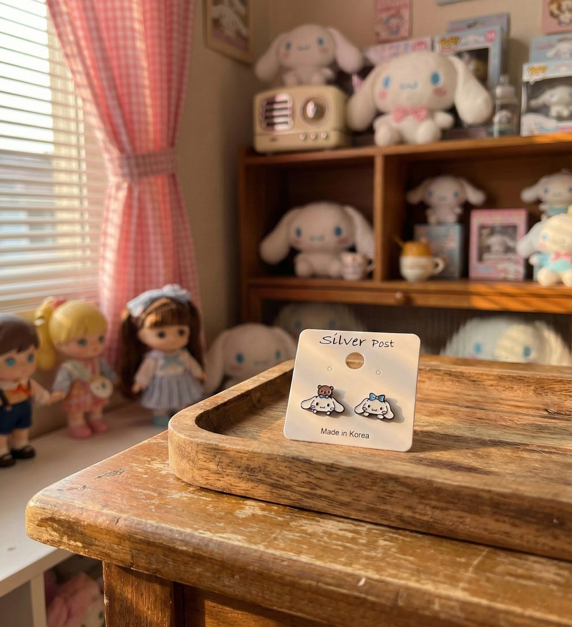 Cinnamoroll character earrings packaged on silver post card with kawaii room background