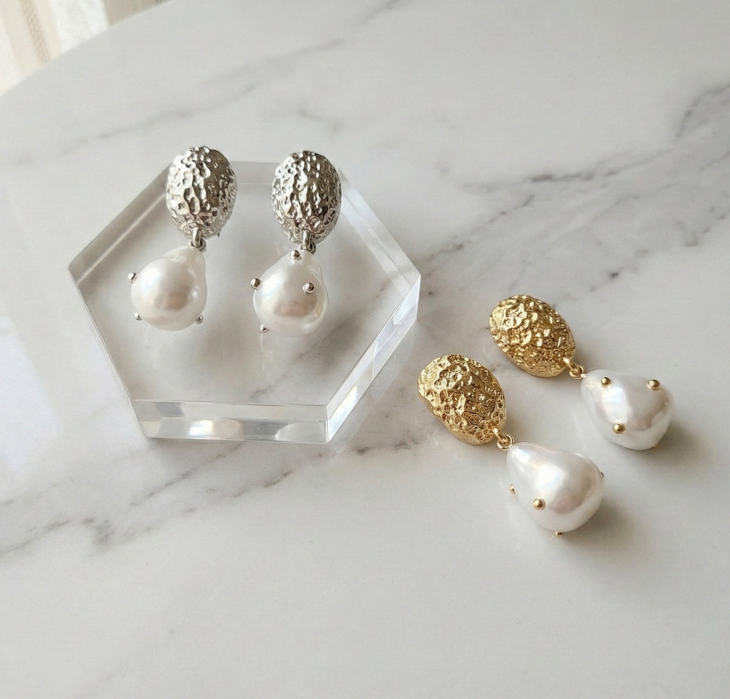 Vintage hammered baroque pearl drop earrings in gold and silver on marble display