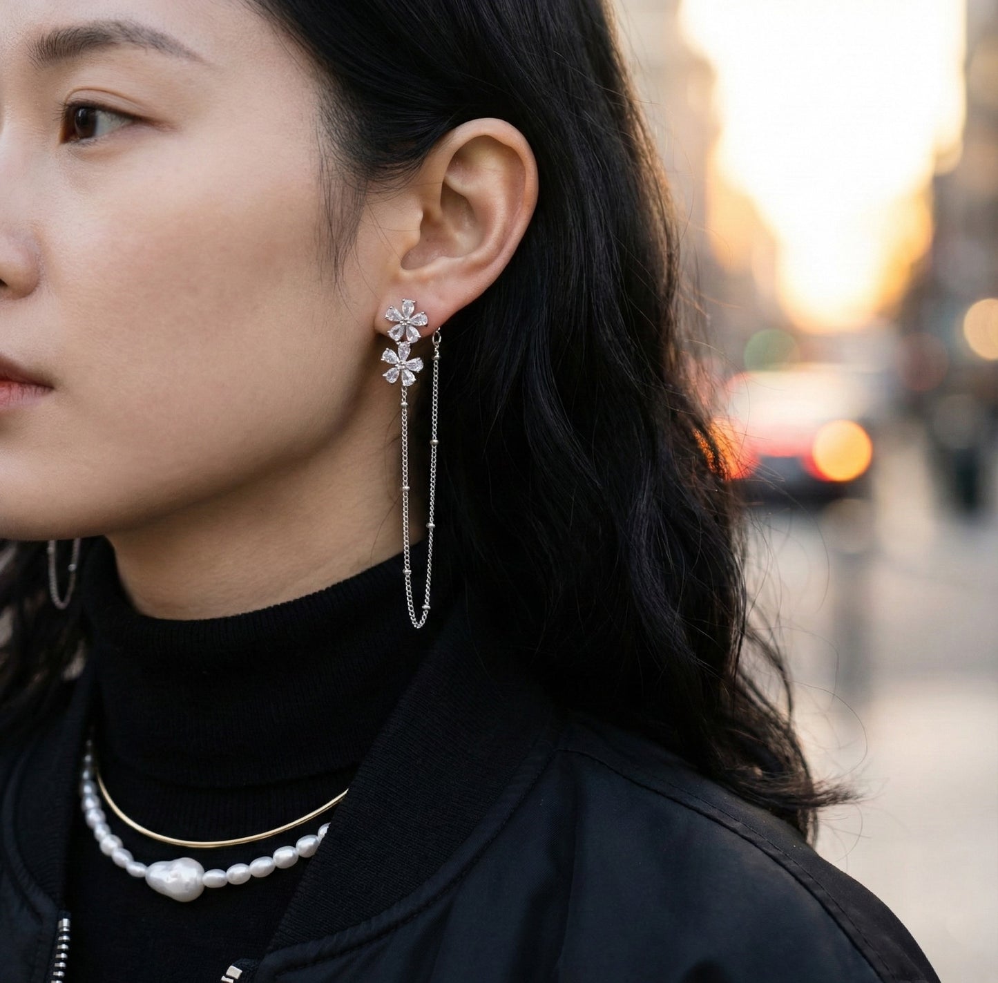 Woman wearing silver floral crystal chain drop earrings with black turtleneck outdoors
