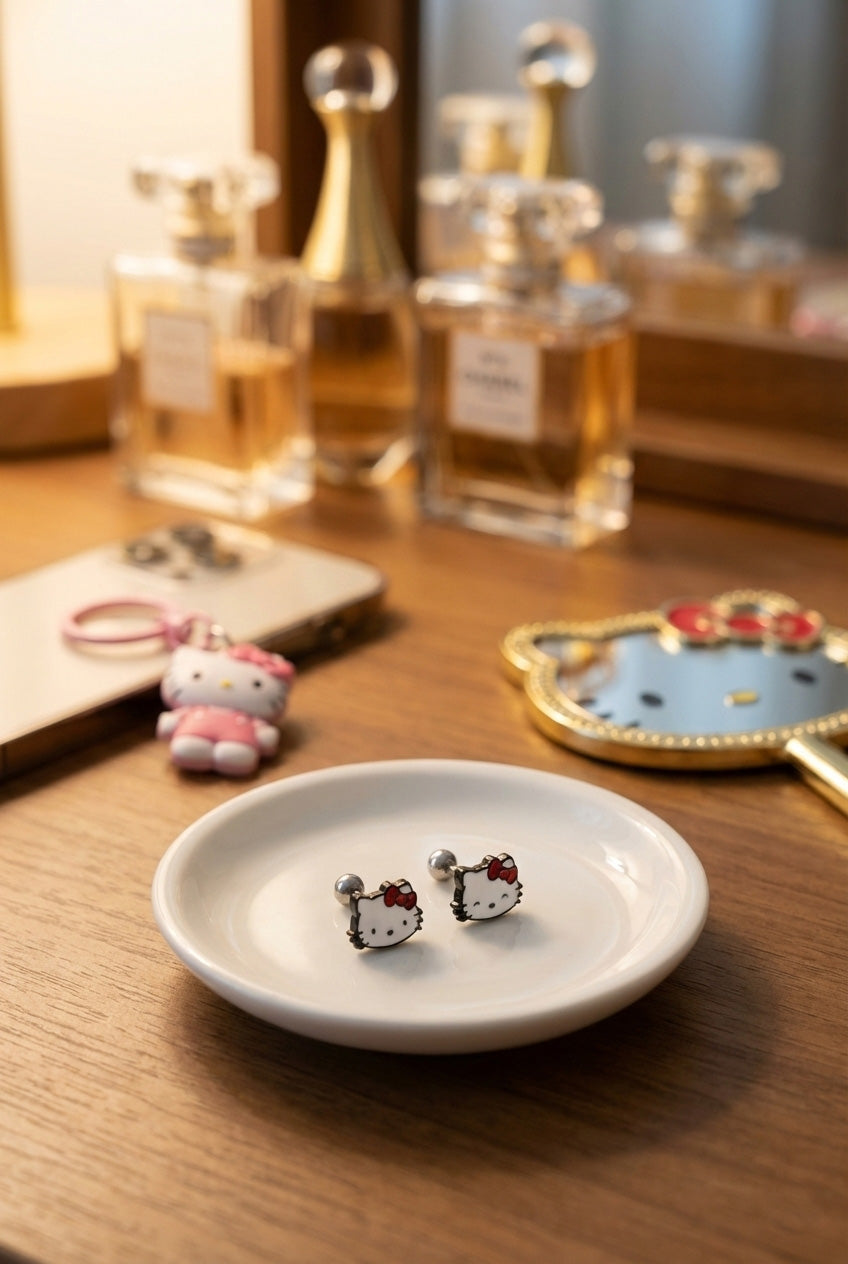 Hello Kitty surgical steel barbell stud earrings on vanity tray with perfume bottles