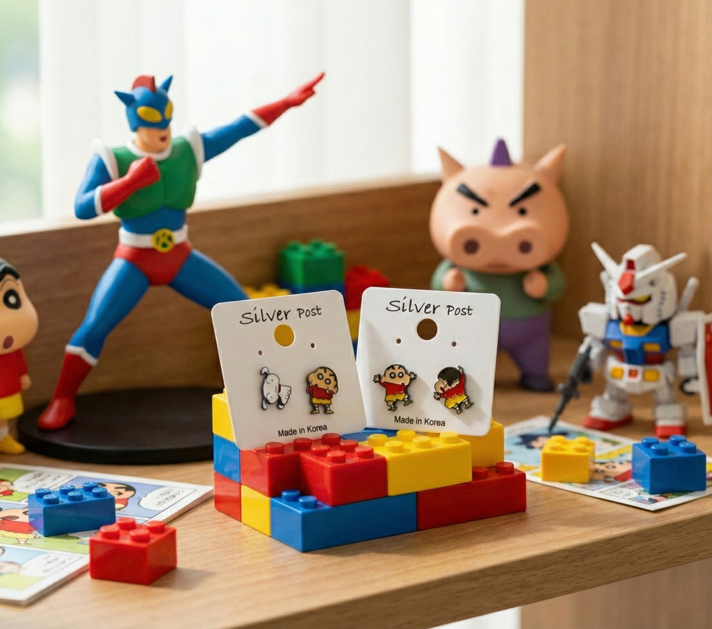 Crayon Shin-chan inspired stud earrings displayed on colorful block toys, surrounded by action figures and building bricks.
