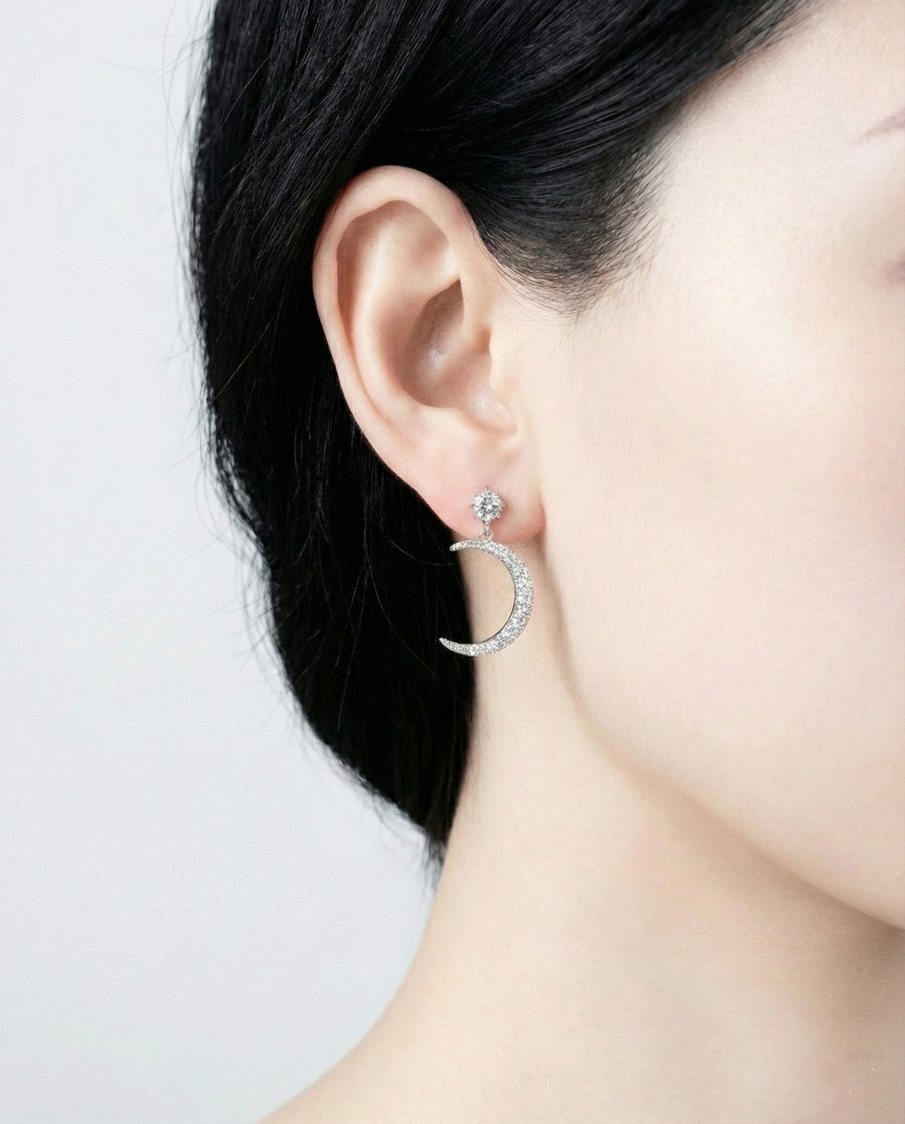 Asymmetric moon and star drop earrings with cubic zirconia on model ear