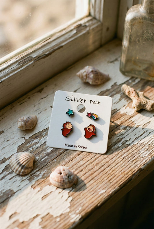 Ponyo earring set with four designs displayed on card near seashells and vintage window