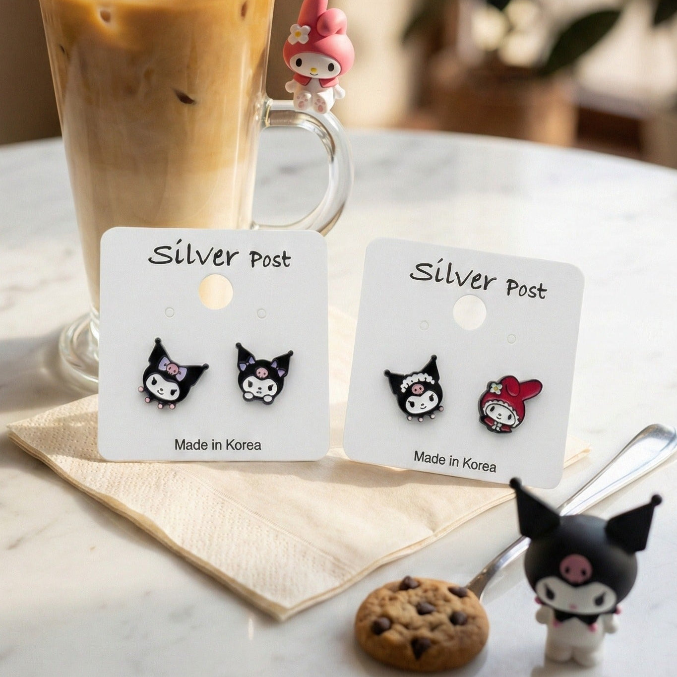 Korean handmade Kuromi and My Melody mismatched earrings with iced coffee and Sanrio figurines on white table