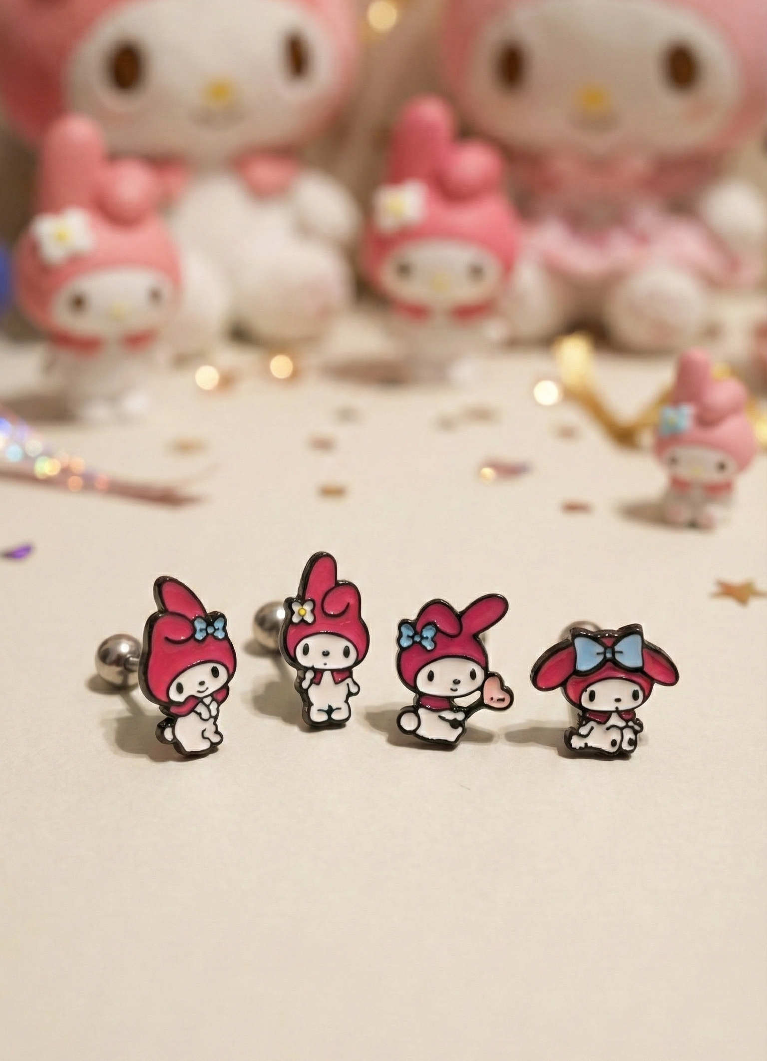Four My Melody surgical steel enamel stud earrings in different poses with Sanrio plushies background