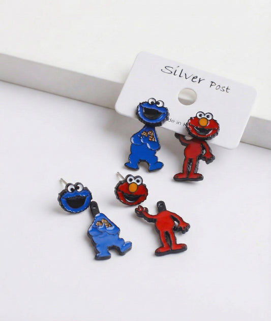 Close-up of Sesame Street Elmo and Cookie Monster 2-way silver post earrings on a white surface, showing both head and full-body parts.