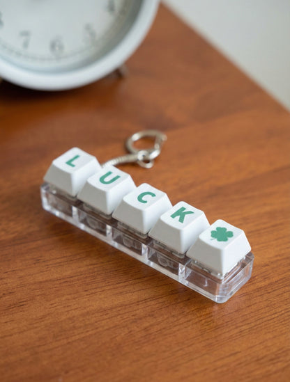 LUCK LED mechanical keyboard keychain with white keycaps and green lettering on wooden table