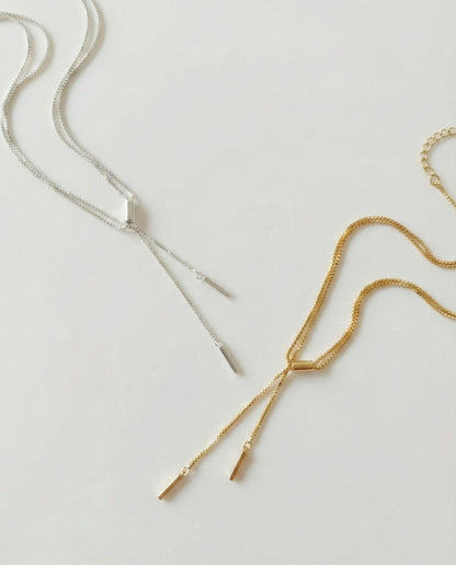 Double row Y-drop stick chain necklaces in silver and gold, laid flat on a white background