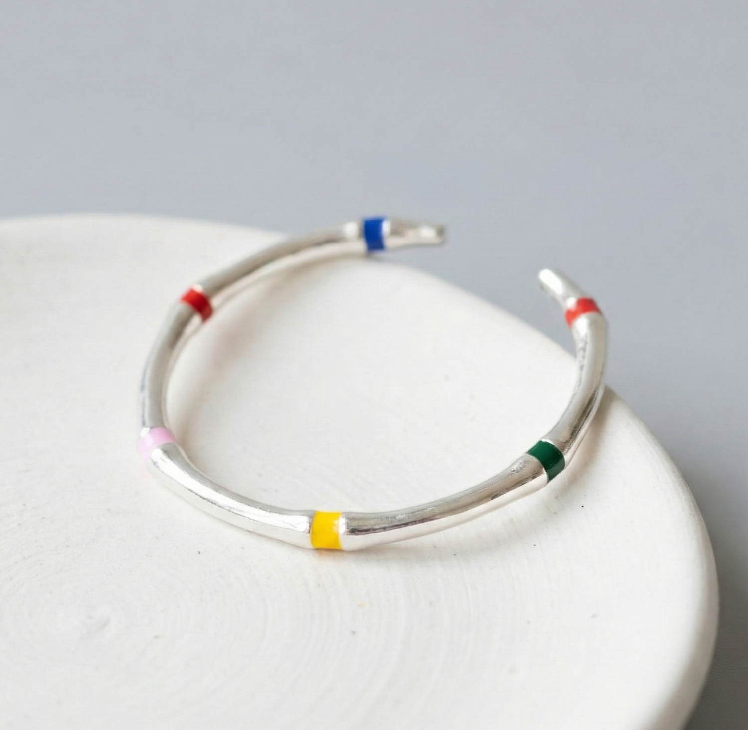 925 sterling silver multicolor enamel open ring displayed on white ceramic bowl, showing all five enamel color accents: red, blue, yellow, green, pink