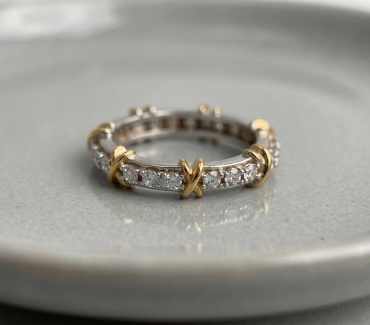 925 sterling silver two-tone eternity band with gold X-cross accents and round cubic zirconia pavé, placed flat on a gray ceramic dish — full product view