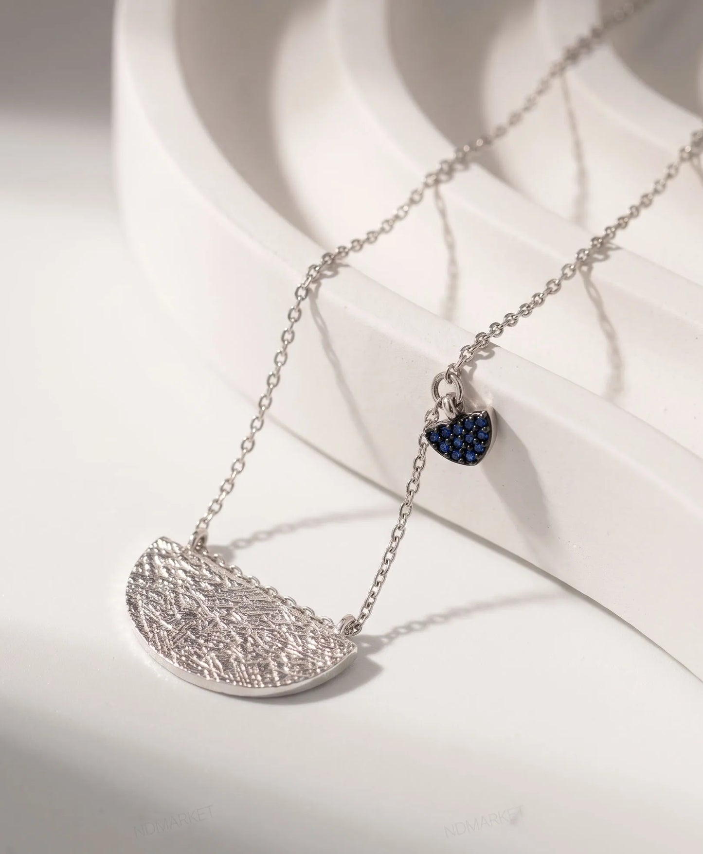 Product flat lay — Textured hammered half-moon pendant close-up, sterling silver 925 tarnish-free necklace detail.