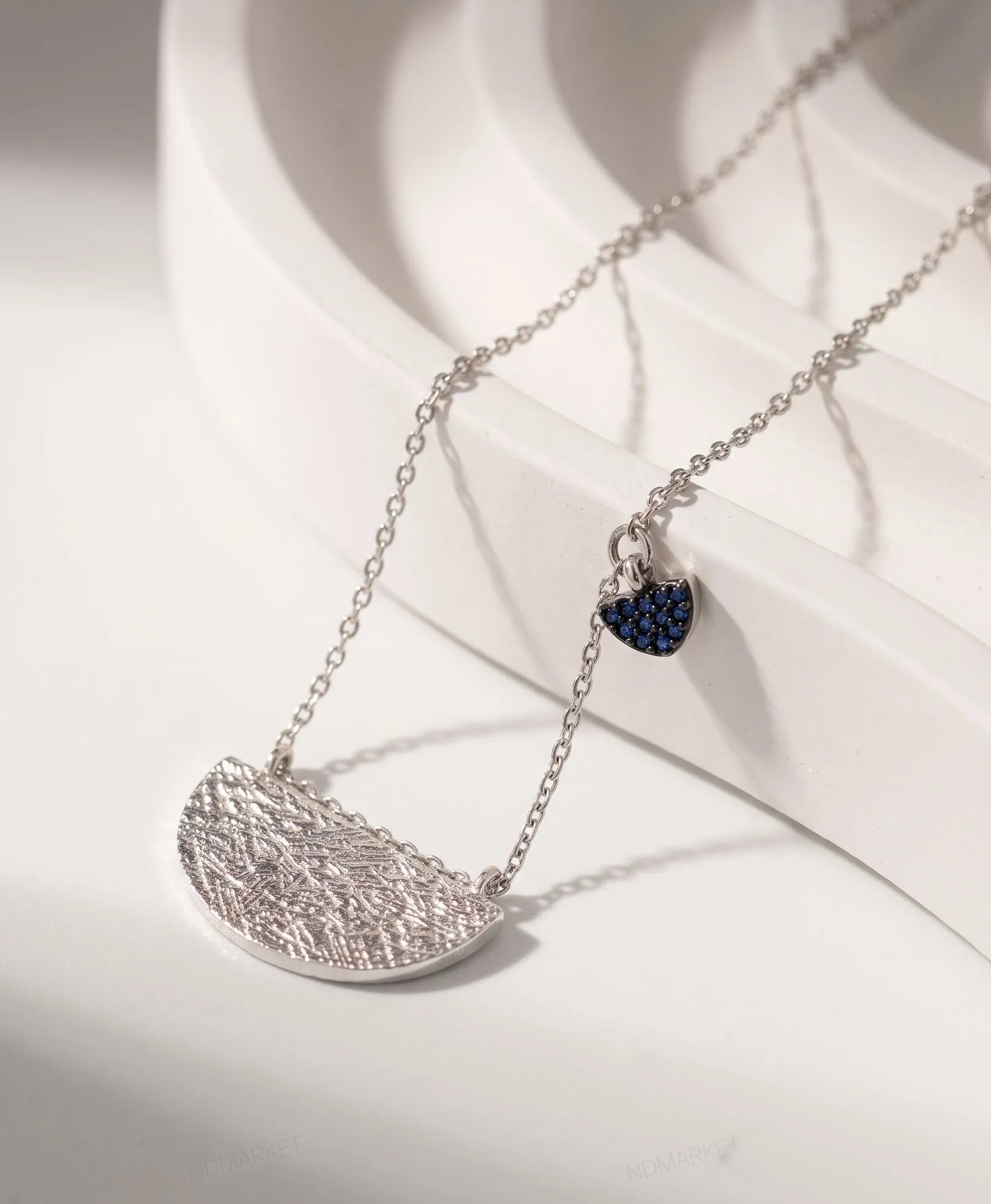 Product flat lay — Textured hammered half-moon pendant close-up, sterling silver 925 tarnish-free necklace detail.