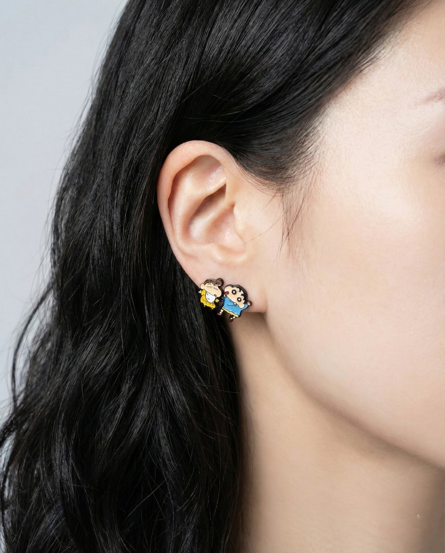 Model wearing Crayon Shin-chan and Himawari character stud earrings on ear closeup