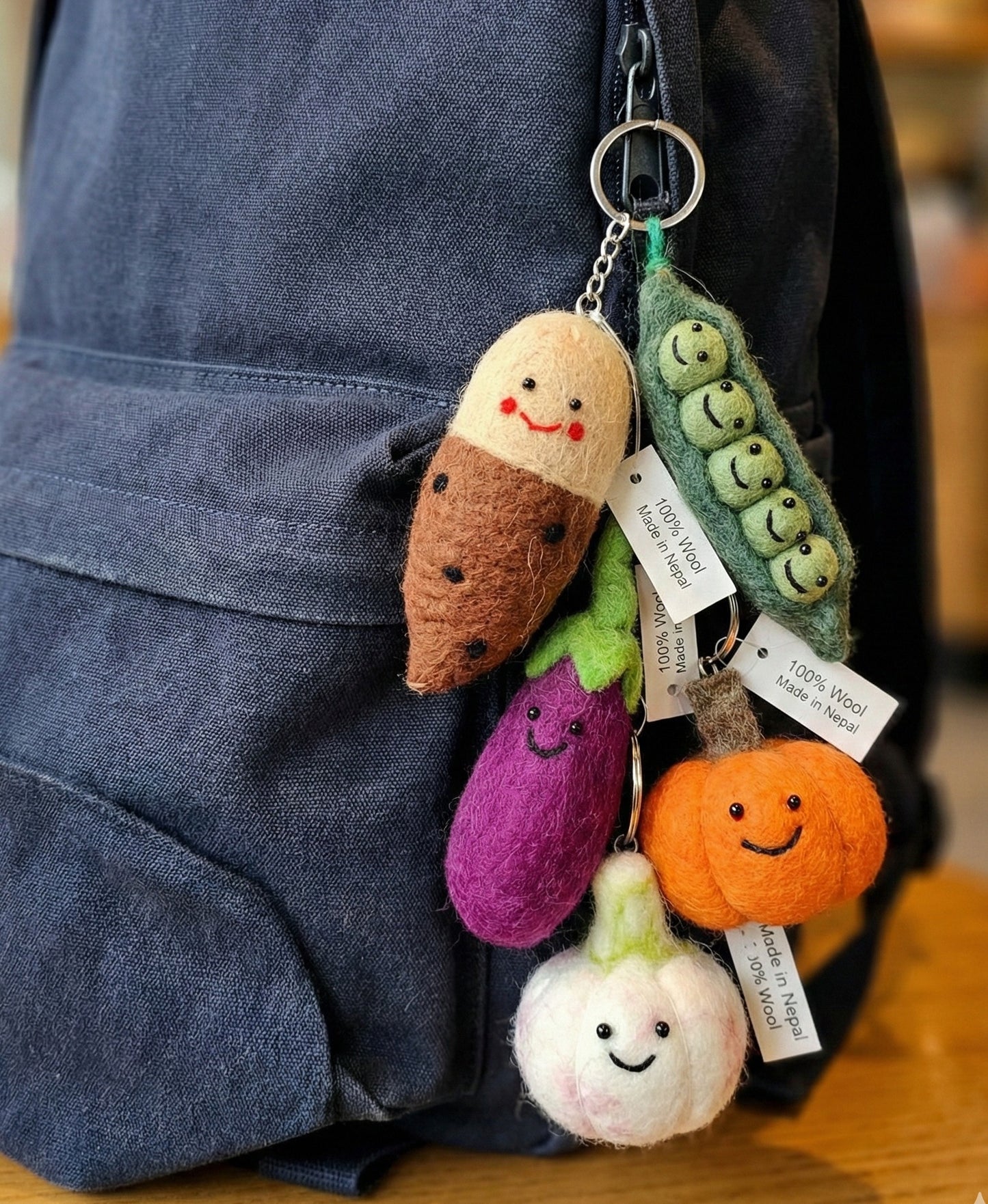 Handmade Nepal wool felt vegetable keychain set hanging on navy blue backpack