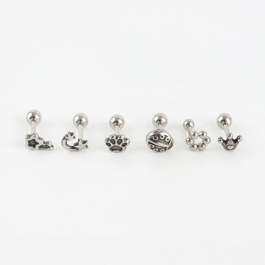 Six surgical steel antique piercings: shooting star, moon star, paw print, ladybug, dot flower, crown on white background