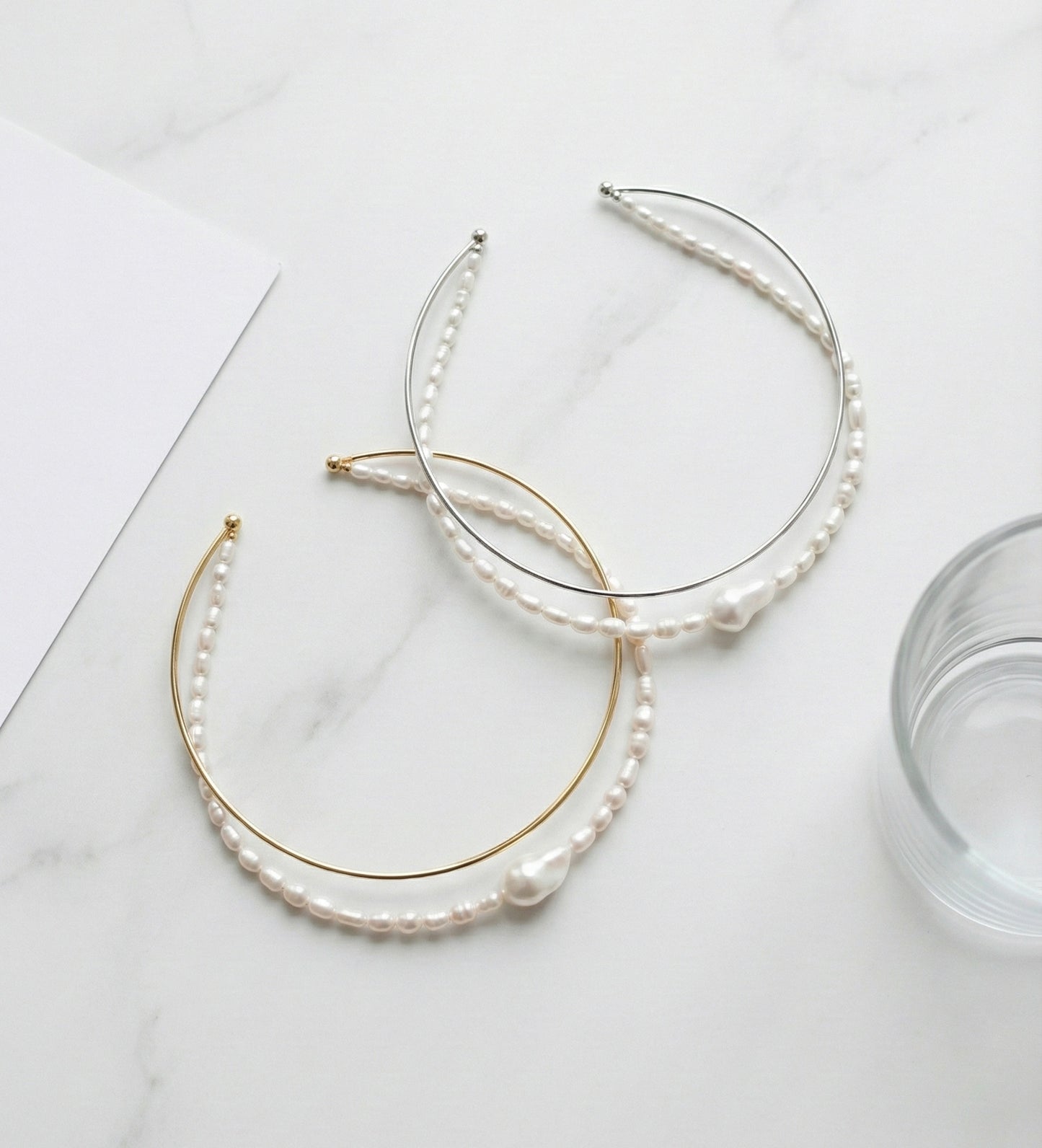 Double strand freshwater pearl and brass wire choker necklace in gold and silver on white marble