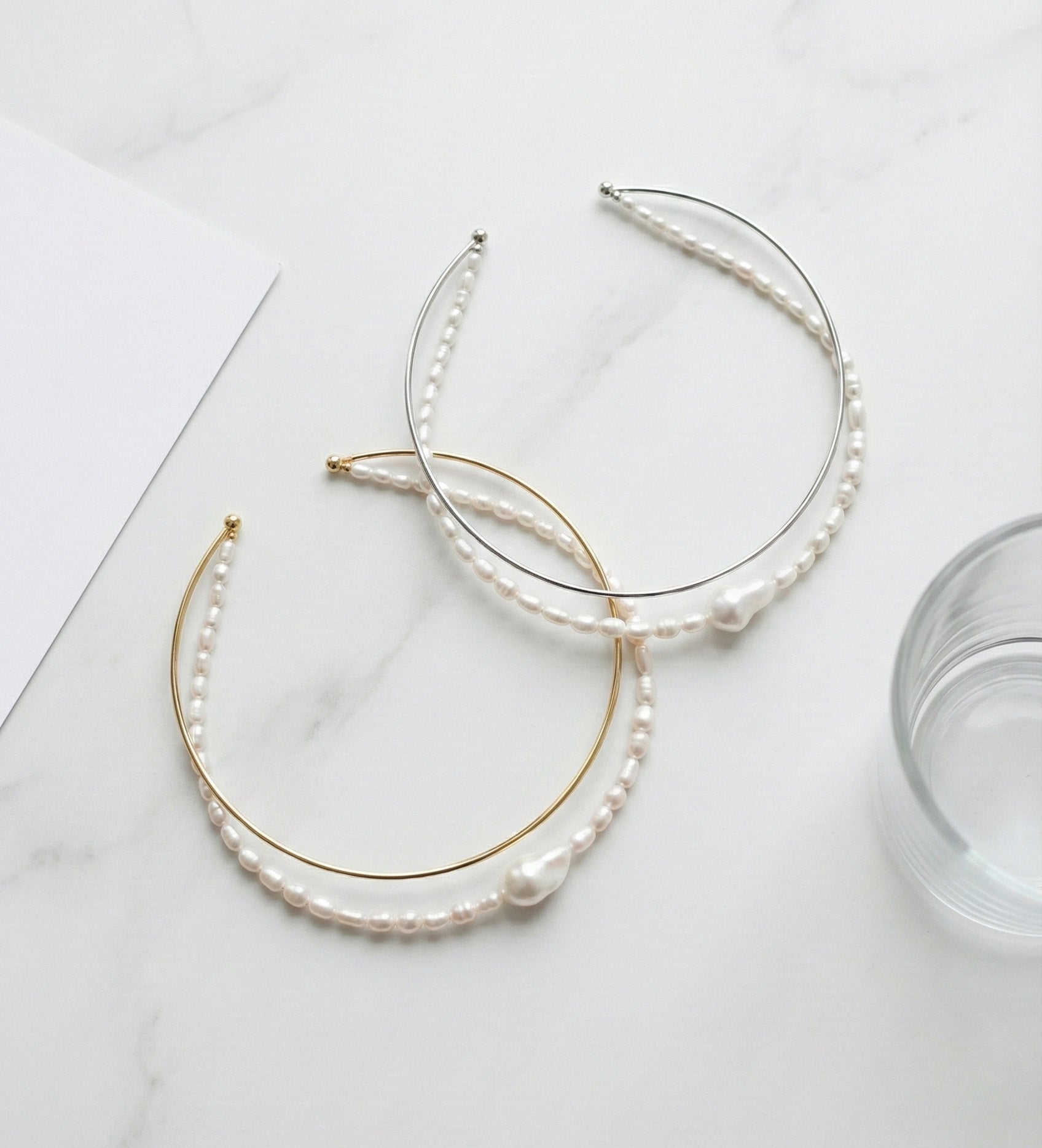 Double strand freshwater pearl and brass wire choker necklace in gold and silver on white marble