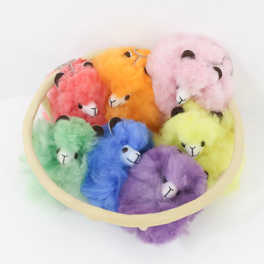 Colorful fluffy keychains in a circular wooden holder on a white background