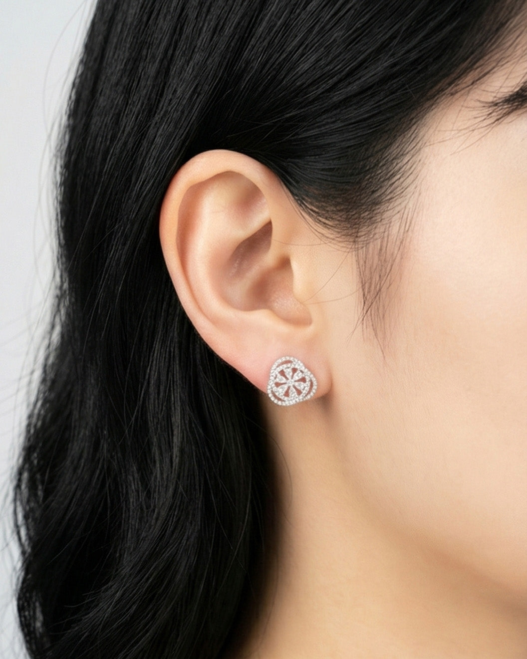 Woman wearing heart-shaped cubic zirconia stud earring with flower motif on earlobe, rose gold plated brass 925 silver posts, Korean elegant jewelry