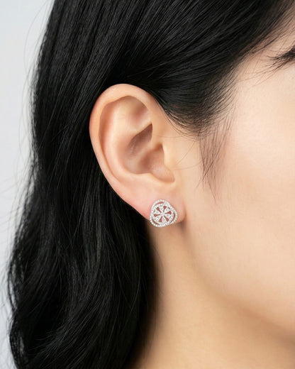Woman wearing heart-shaped cubic zirconia stud earring with flower motif on earlobe, rose gold plated brass 925 silver posts, Korean elegant jewelry
