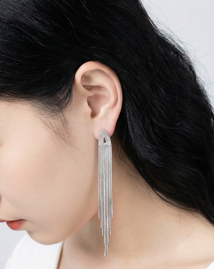 Woman wearing 10cm long silver chain tassel fringe drop earrings, shoulder duster statement jewelry