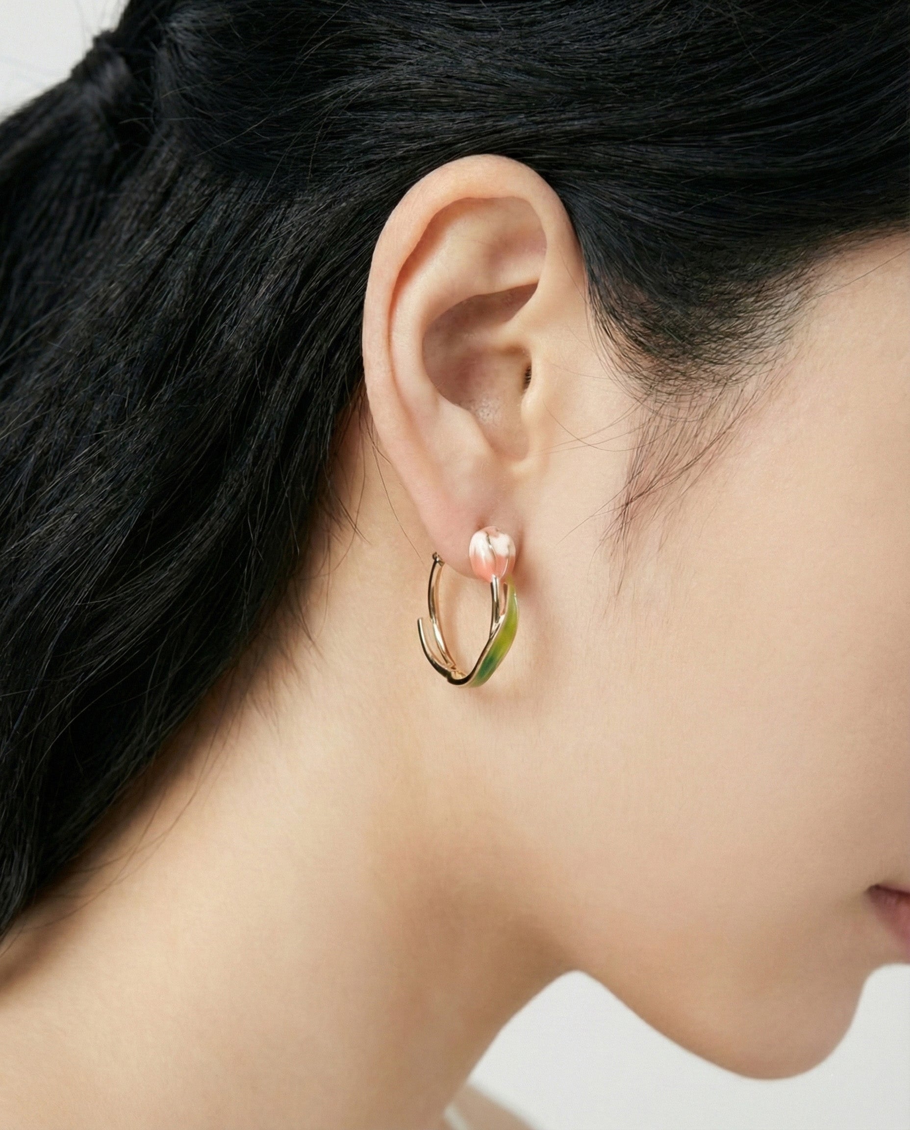 Woman wearing blue gradient tulip hoop earrings with 3D flower design