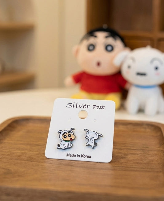 Crayon Shin-chan and Shiro mismatched stud earrings on silver post card, made in Korea, displayed with plush toys