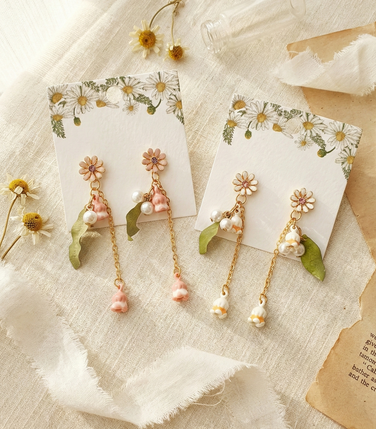 Two pairs of handmade Lily of the Valley drop earrings in pink and white on botanical cards.