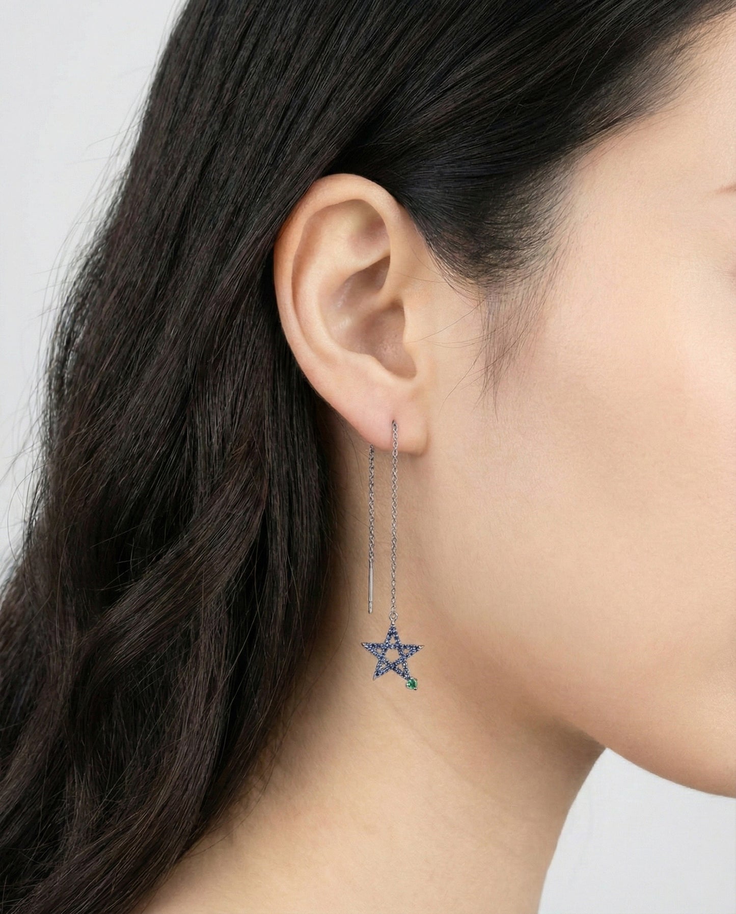 Asymmetrical blue star drop earrings on model ear showing long chain dangle design
