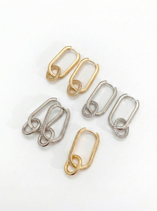 Gold and silver brass oval link drop huggie hoop earrings with pave cubic zirconia on white background