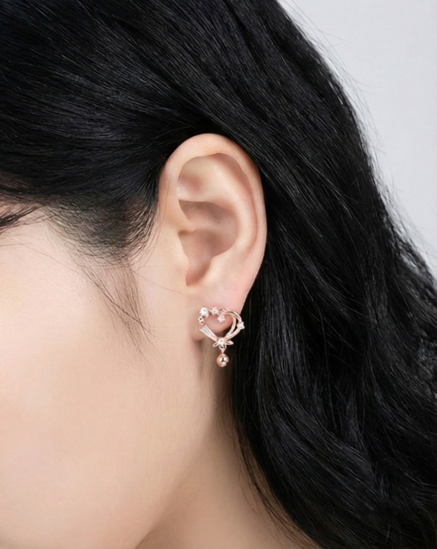 Woman wearing silver heart drop earrings with cubic zirconia crystals and ball pendant, side profile showing delicate lightweight design, 925 sterling silver posts hypoallergenic, Korean handmade jewelry