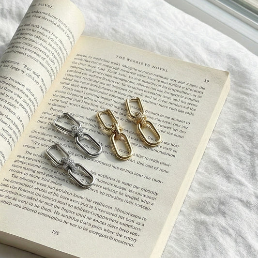  Luxury gold and silver chain link drop earrings with pavé knot detail on book pages