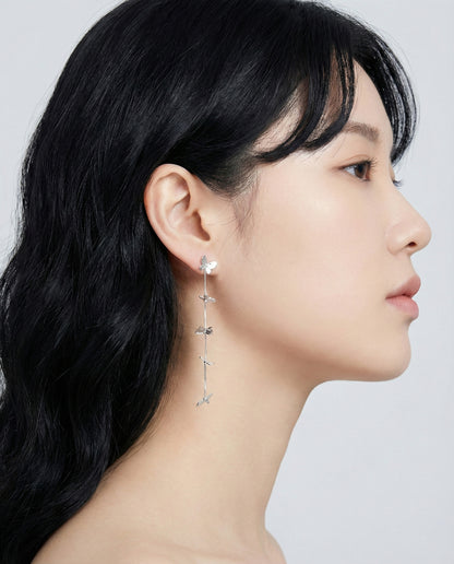 Woman wearing silver butterfly long drop chain earrings cascading down neck